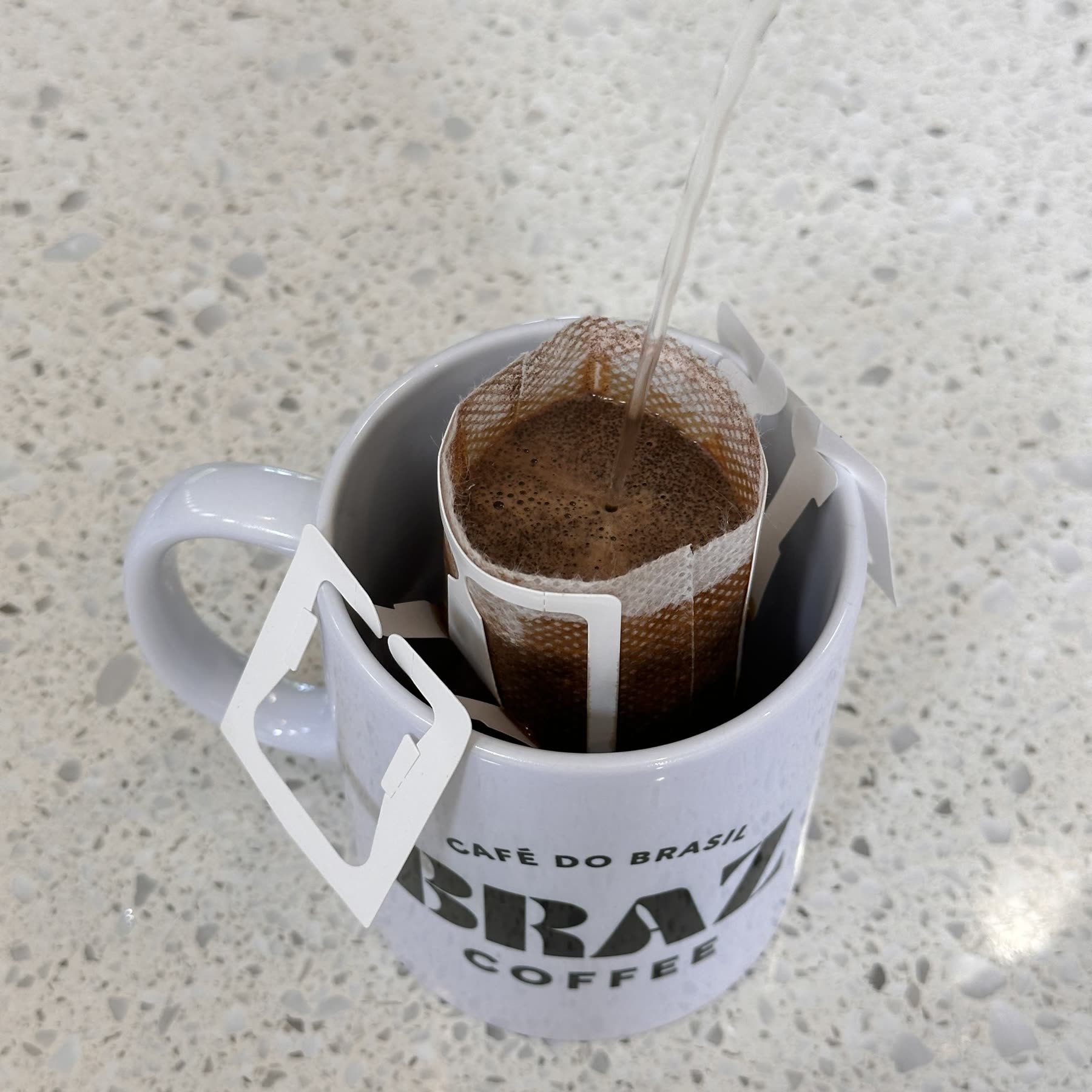 Hot water pouring into a Braz drip coffee bag hanging in a Braz mug